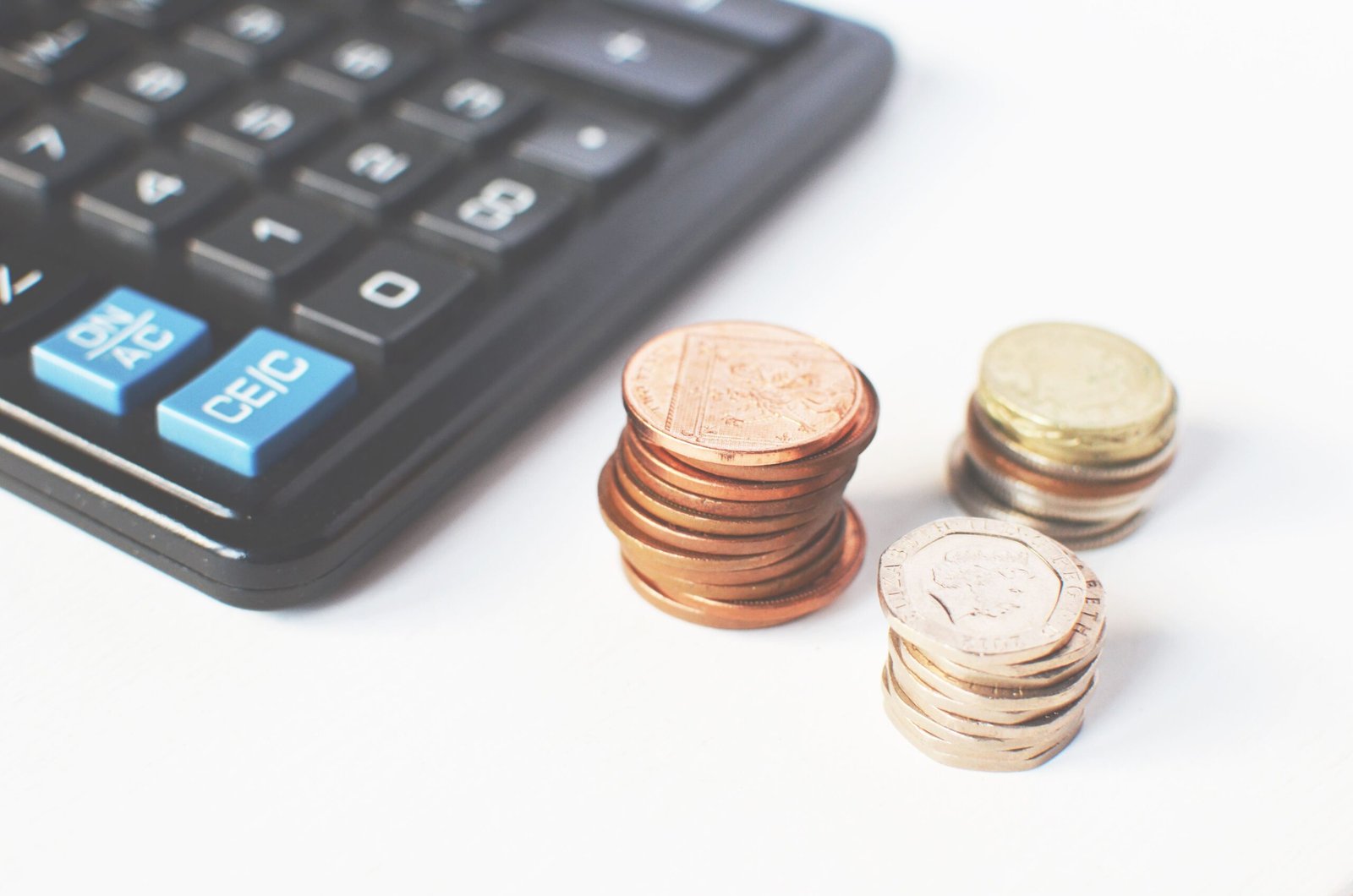 Moedas empilhadas e calculadora, representando contracheques